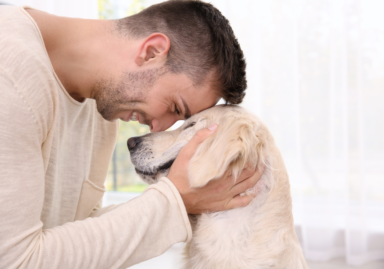 Ein Mann und ein Hund drücken glücklich die Gesichter aneinander.